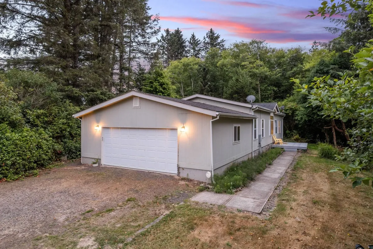 This image captures the exterior of one of the lake homes, framed by a peaceful driveway and surrounded by tall trees. The setting is tranquil, highlighting the secluded nature of the property and the ample outdoor space available for group activities and relaxation.