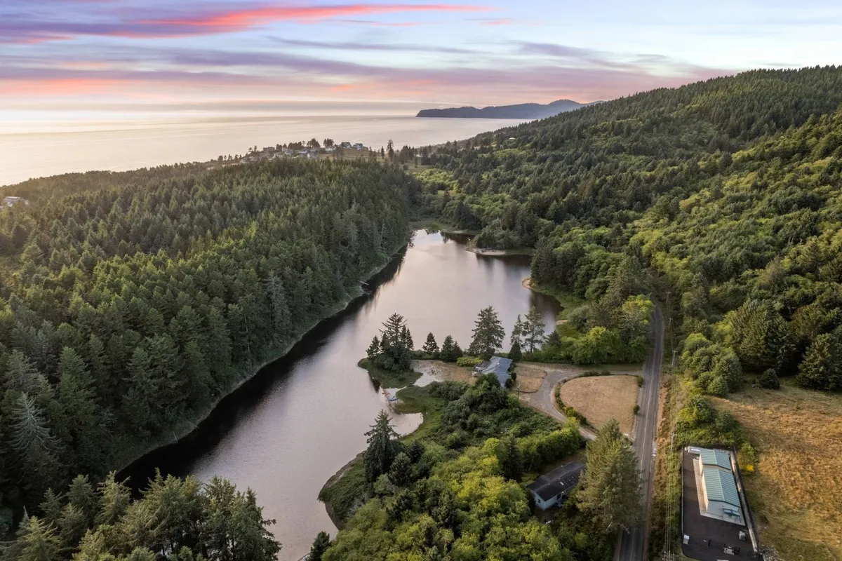 A wide-angle view of the lake framed by forest and mountains, with the sun setting over the water. The landscape invites exploration and water activities such as kayaking and fishing, while the tranquil setting underscores relaxation.