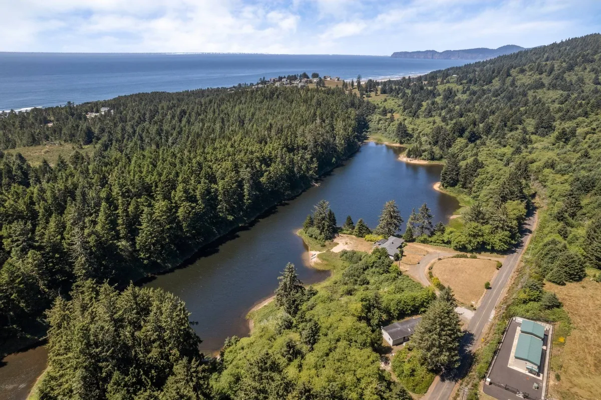 A panoramic vista with an expansive ocean view, lush green forest, a serene water body, and a winding scenic road. The landscape suggests both proximity to nature and opportunities for outdoor recreation, such as hiking, fishing, or simply enjoying the sunrise.