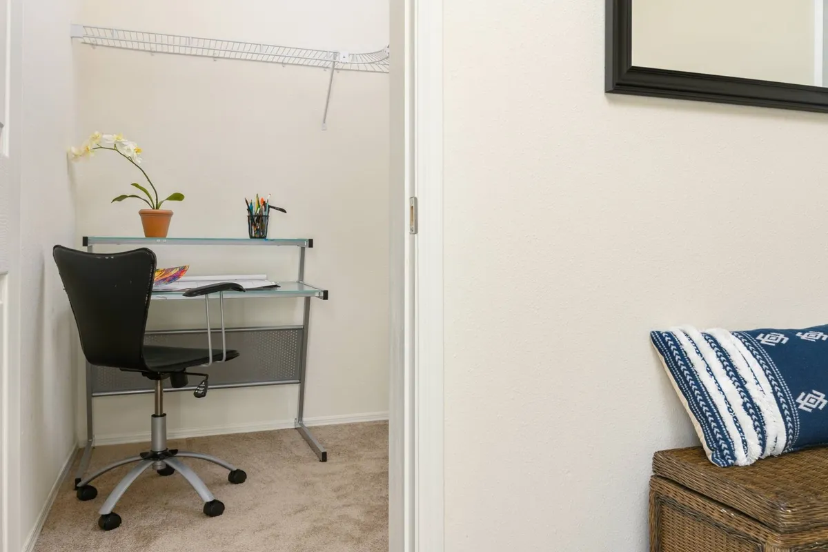 A dedicated workspace within the bedroom, featuring a modern desk, a comfortable chair, a potted plant, and a woven basket beneath. The setup is minimal and serene, ideal for remote work or creative activities while enjoying privacy.