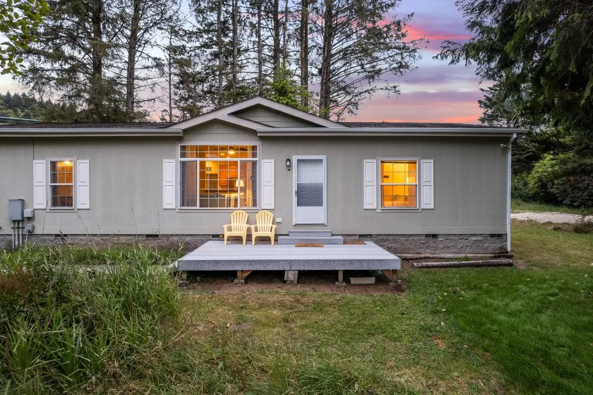 The exterior view of the house features bright yellow chairs on a spacious deck, large windows, and a visible front door. The deck opens onto a safe, grassy yard, suggesting a secure space where pets can enjoy the outdoors under watchful eyes.